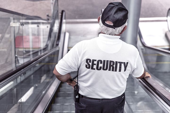 Older man wearing security shit going down escalator